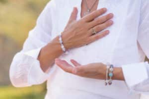 Close up of woman's hands; one on her heart and the other open with her palm up in acceptance.