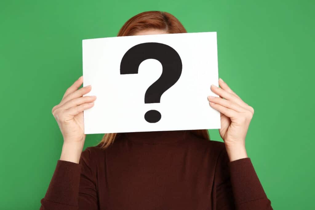 A green background with a woman hold a large white card with a question mark in front of her face.